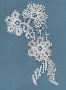 Lace flowers in white thread on green background